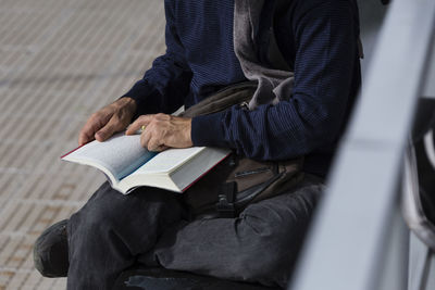 Midsection of man reading book