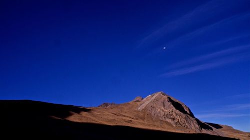 Low angle view of mountain against blue sky