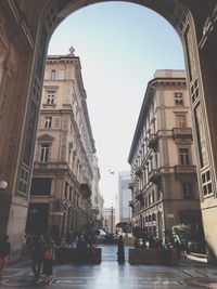 People walking on street amidst buildings against clear sky