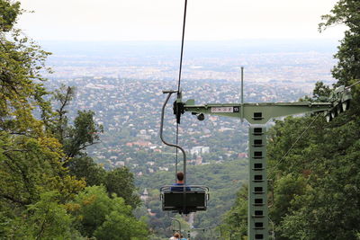 Overhead cable car in city against sky