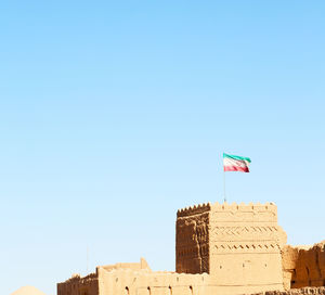 Low angle view of flag on building against clear blue sky