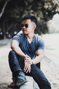 Young man wearing sunglasses sitting outdoors