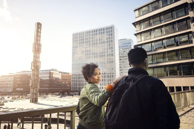 Portrait of teenage girl walking with friend on bridge in city