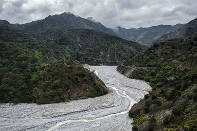 Scenic view of river by mountains against sky