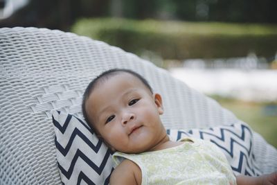 Close-up portrait of baby girl leaning on chair at yard