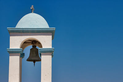 Low angle view of bell tower against blue sky and building