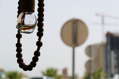 Close-up of bead necklace hanging against sky