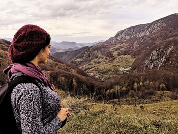Side view of man looking at mountains against sky