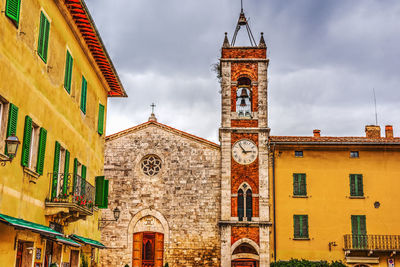 Low angle view of clock tower amidst buildings against sky