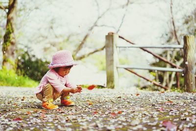 Full length of cute baby girl playing with dry leaves at park during autumn