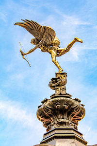 Low angle view of angel statue against cloudy sky