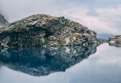 Reflection of rocks in lake against sky