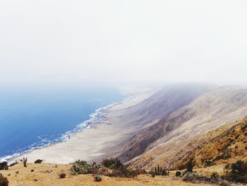 Scenic view of sea and mountains against clear sky