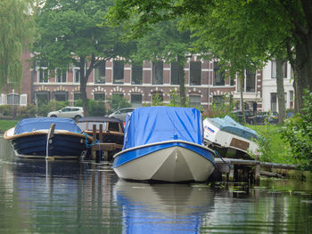 Boats moored in lake against trees in city