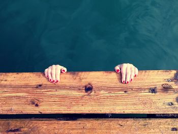 Cropped image of woman hanging on jetty over lake