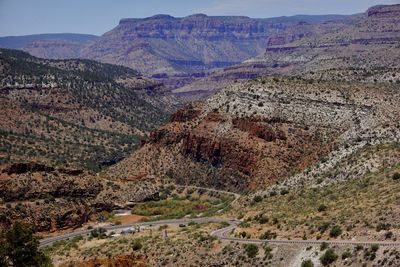 A road curves the the rough mountain desert terrain of the american southwest.