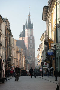 People walking on street in city against clear sky