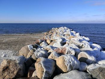 Rocks in sea against blue sky