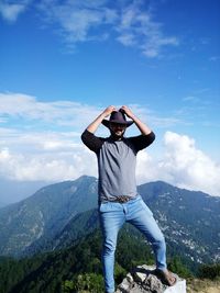 Low angle view of man standing on mountain against clouds