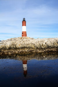 Lighthouse on puddle against sky