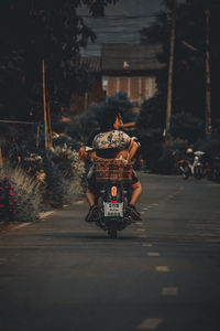 Rear view of man riding motorcycle on road