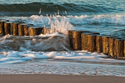 Waves splashing wooden post in sea