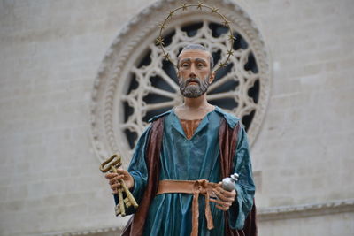 Full length of a person holding cross against wall