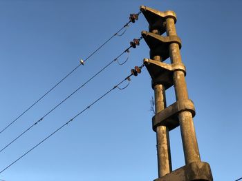 Low angle view of power lines against clear blue sky