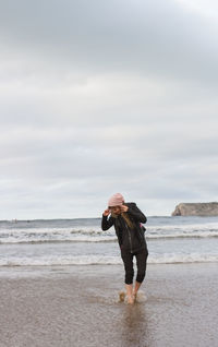 Full length of woman walking on beach against sky