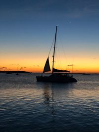 Silhouette sailboat sailing on sea against sky during sunset