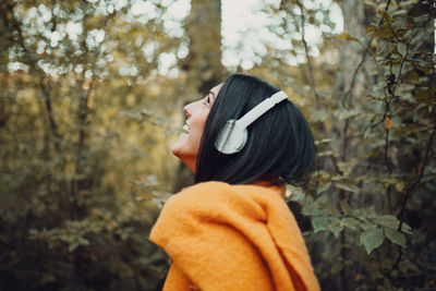 Side view of woman standing against trees