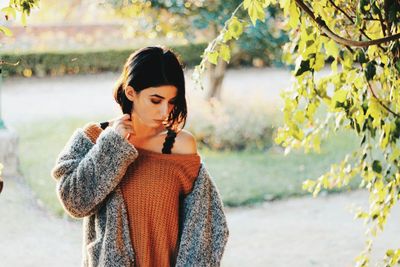 Young woman standing by tree against plants