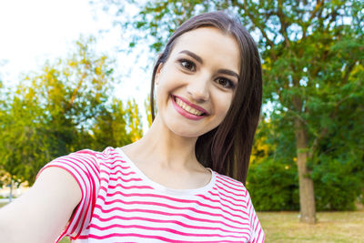 Portrait of smiling young woman against trees