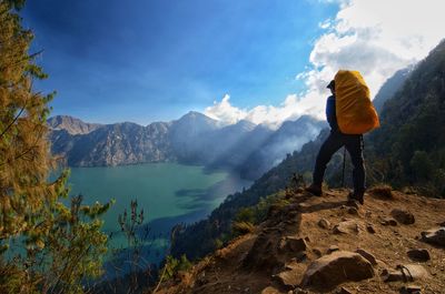 Rear view of man standing on mountain against sky