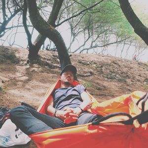 Young man sleeping on hammock against trees