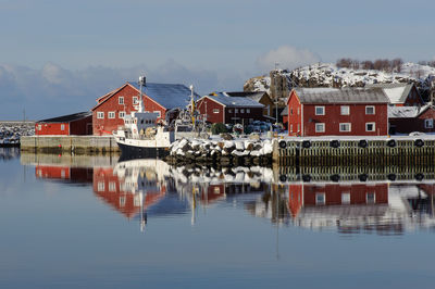 Houses by lake against sky