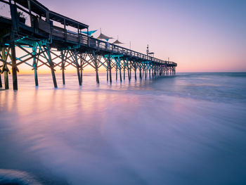 Pier over sea against sky during sunset