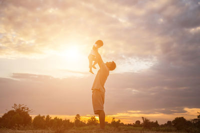 Man standing on field against sky during sunset