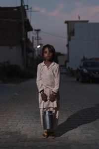 Young woman standing on street against sky