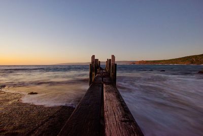 Wooden posts on beach against clear sky