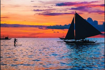 Silhouette man on sea against sky during sunset