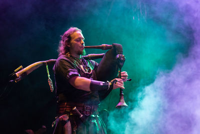 Young man with arms raised at music concert