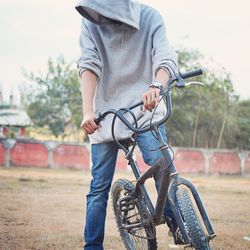 Young man standing with bicycle on field