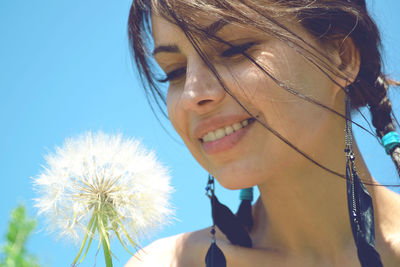 Close-up of young woman against blue sky