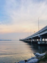 Bridge over sea against sky during sunset