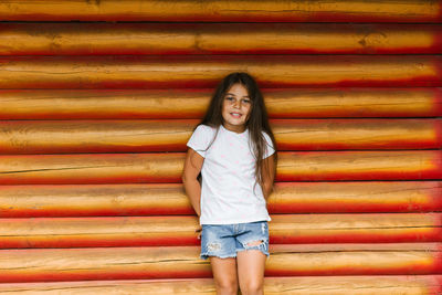 Beautiful cute baby girl posing on the background of a log wall