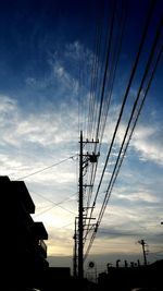 Low angle view of electricity pylon against cloudy sky