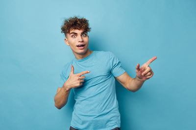 Portrait of young man gesturing against blue background