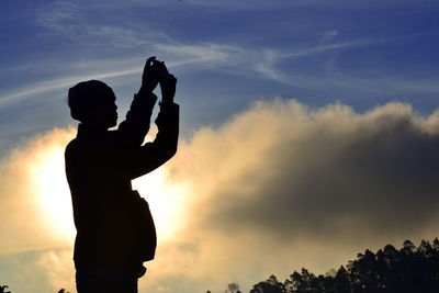 Silhouette man photographing against sky during sunset