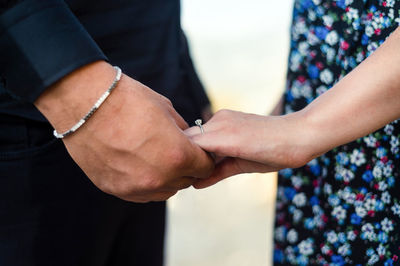 Man holding woman's hand, solitaire on woman's finger and close-up